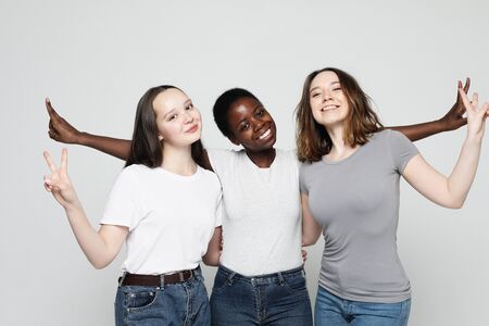 Close-up portrait of charming multiracial girls over grey background