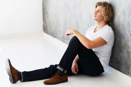 Attractive young male model sitting on the floor, casual wear and calm look