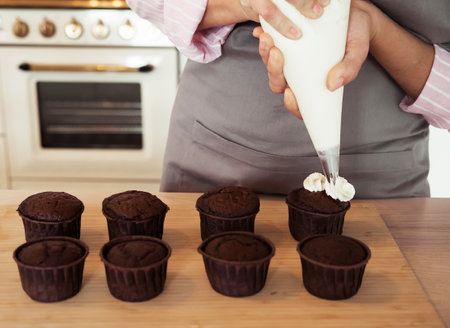 Young woman pastry chef decorates cupcakesの写真素材