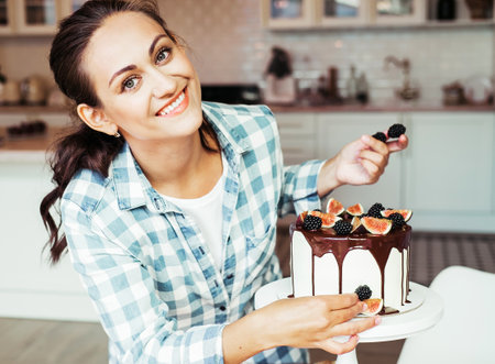 Pastry chef decorates the cake with berries and figs.の写真素材