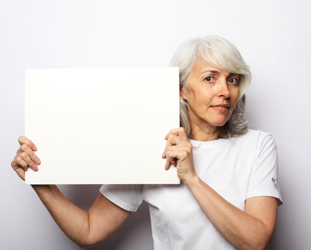 Portrait of happy senior woman with blank advertising board or copy spaceの写真素材