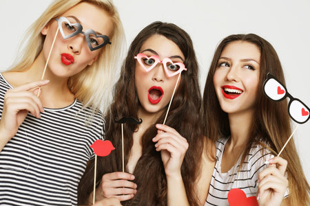Three young women holding paper party sticksの写真素材