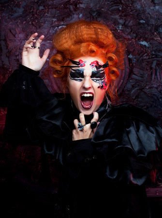 Young redhead woman in witch costume screams and rages. Halloween and party concept. Close up.の写真素材