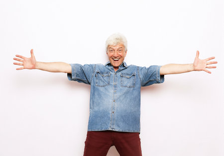Senior gray-haired man wearing casual clothes very happy and excited doing winner gesture with arms raised, smiling and screaming for success. celebration concept. Over white background.の写真素材