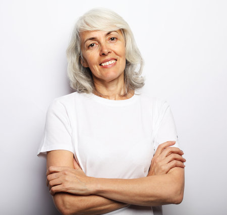 Old people, lifestyle and modern lifestyle concept. Portrait of senior gray-haired woman with cute smile over white backgroundの写真素材