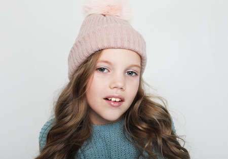 Laughing cute girl portrait over white background. Little child wearing blue sweater and winter hat...
