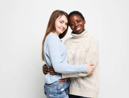 young multiracial women standing together and smiling at camera isolated over white backgroundの写真素材
