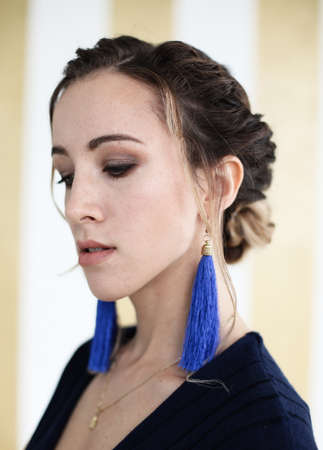 Beautiful young woman with blue earrings, close up