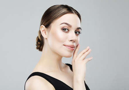Beautiful woman with perfect makeup on gray background. Beauty and skin care concept. Close up.
