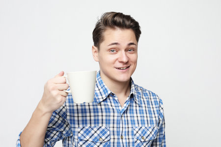 Cheers. Young smiling handsome man with a white cup.の写真素材