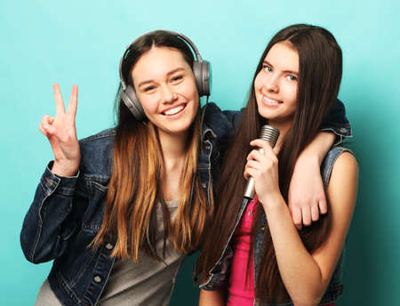 two young teenager friends standing together and having fun. Showing signs with hands. Looking at...