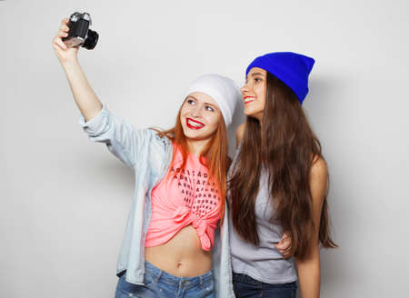 Pretty girls friends holding a vintage camera on a white background.の写真素材