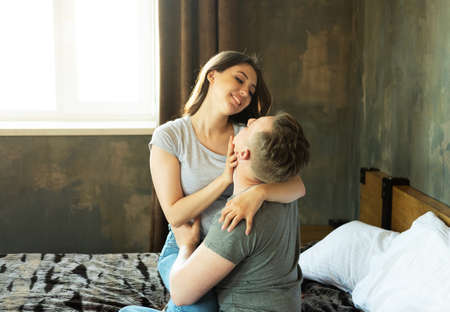 Young beautiful couple is sitting on the couch and hugging. Happy family life.の写真素材