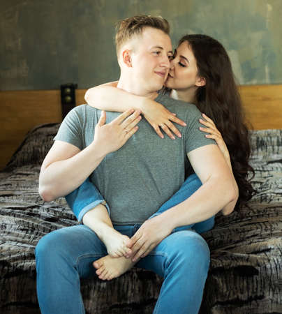 Young beautiful couple is sitting on the couch and hugging. Happy family life.の写真素材