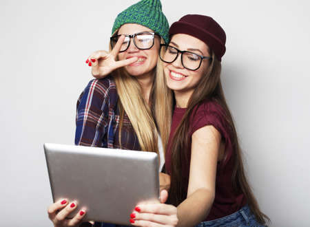 two girls friends taking selfie with digital tablet over grey backgroundの写真素材