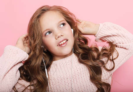 People, childhood and fashion concept: little girl child wearing pink sweater over pink background