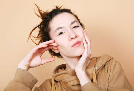Young brunette woman model posing over beige background.の写真素材