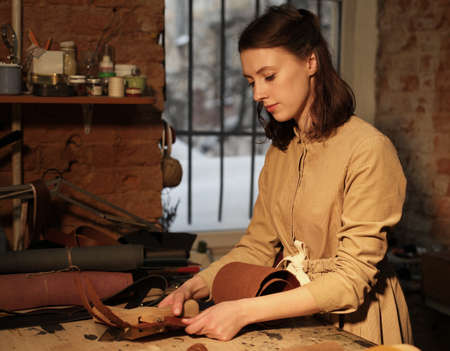 Lifestyle, freelance and home business concept: young woman works in a bag making studio, cuts out...