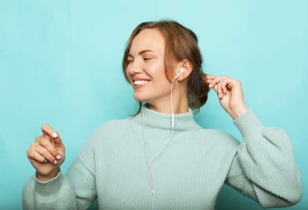 Lifestyle, emotion and people concept: beautiful young woman in a blue sweater smiles and dances,...