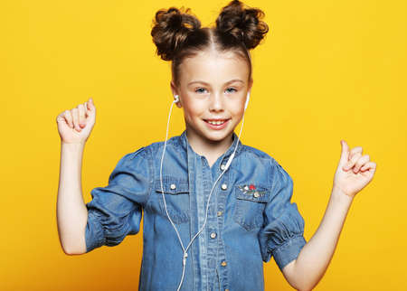 emotion, childhood, tehnology and people concept: happy girl with headphones listening to music