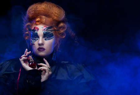 Red-haired young woman in witch costume. Creative makeup for masquerade.の写真素材