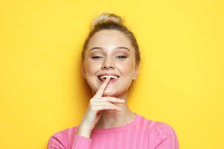 Young and cheerful blonde woman smiling and laughing looking at the camera over yellow background