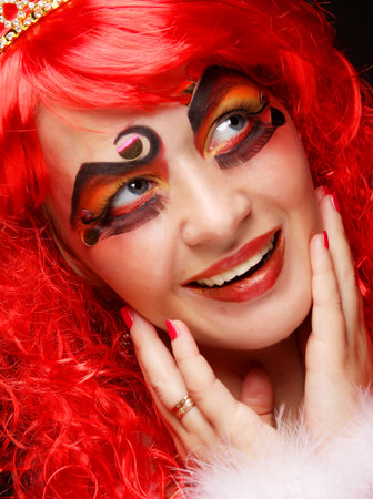 Charming woman in red curly wig and crown.の写真素材