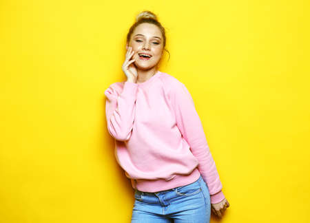 Young and cheerful blonde womanwearing pink shirt smiling and laughing over yellow background