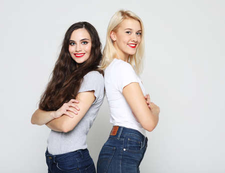 lifestyle and people concept: Two young girl friends standing together and having fun. Looking at camera.の写真素材