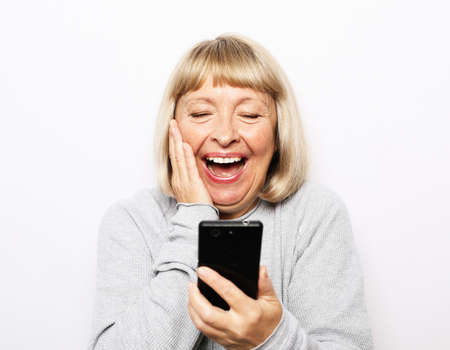 Pretty senior woman in casual outfit using modern smartphone