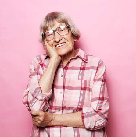 Grey haired old nice beautiful laughing woman wearing glasses. Isolated over pink backgroundの写真素材
