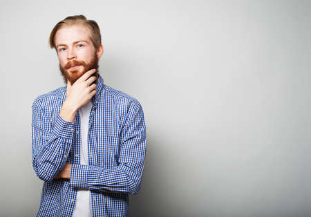 Handsome young bearded man in smart casual wear looking at camera, over grey backgroundの写真素材