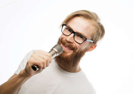 Young man with a beard wearing a white shirt and glasses holding a microphone and singing.の写真素材