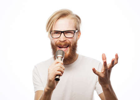 Image of a handsome man singing to the microphone. Emotional portrait of an attractive guy with a beard on white backgroundの写真素材