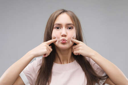 Portrait of beautiful young woman happiness standing finger touch cheek on gray background