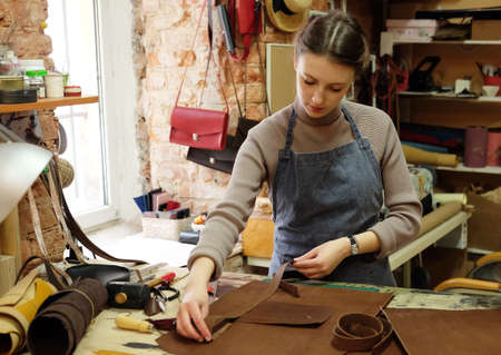 Lifestyle, freelance and home business concept: young woman works in a bag making studio