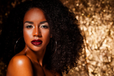 Beauty portrait of african american woman with bright makeup. Gold studio background.の写真素材