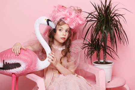 Adorable little girl in a fairy costume and make-up holding a flamingo, pink tones, fairy tale, dream.の写真素材