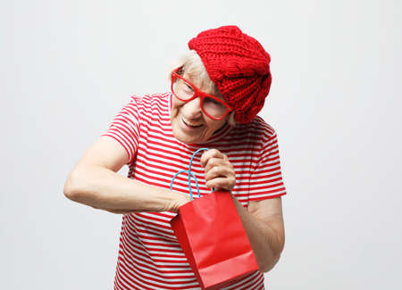 lifestyle and people concept: elderly woman pulls out a gift from the bagの写真素材