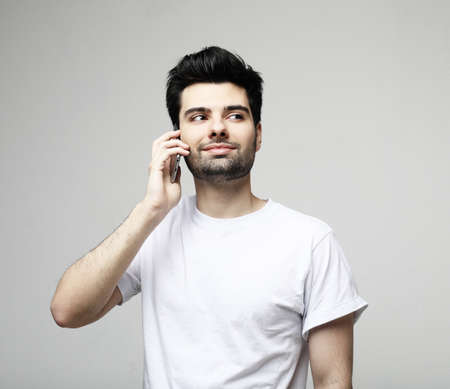 tehnology, emotion and people concept: Smiling young man talking by smartphone, close upの写真素材
