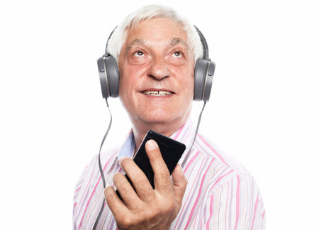 Old man wearin striped shirt listening to music with headphones on white background, close upの写真素材