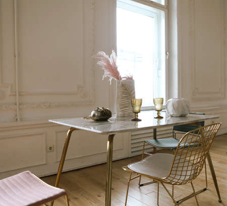 Elegant interior, marble table, stylish chairs. On the table is a vase with pink dry flowers and...