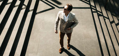 Business, people and success concept: Handsome smiling young business man holding laptop computerの写真素材