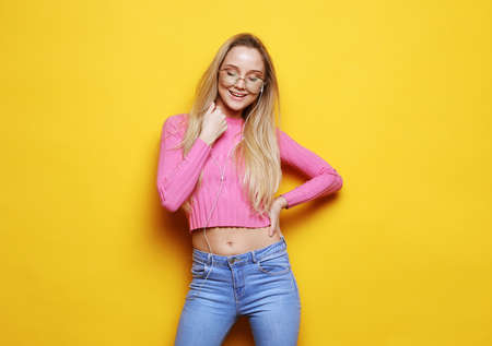 young beautiful female wearing pink sweater looking at camera smiling laughing over yellow...