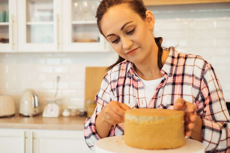 Cooking, Home Business, Freelance, People and Hobbies concept: Young woman Cutting Cake on Layers. Making Layer Cake.の写真素材