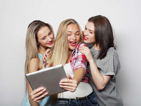 Three young women friends taking selfie with digital tablet over gray backgroundの写真素材