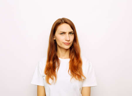 Young beautiful redhead woman wearing white t-shirt over white background skeptic and nervous, disapproving expression on face. negative person.の写真素材