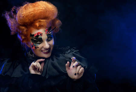 Halloween party. Young redhead woman dressed as a witch. Carnival makeup and hairstyle.