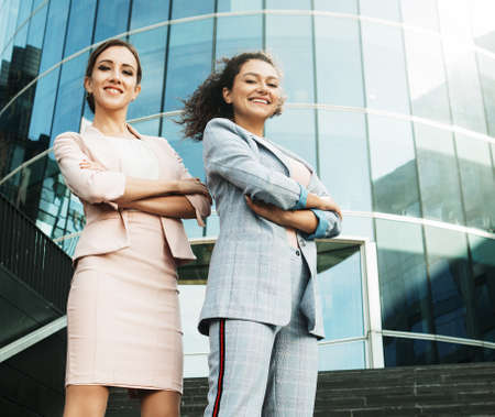 Business, people and lifestyle concept: two office workers standing together outdors near modern business building.の写真素材