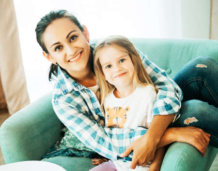 Loving young mother laughing hugging smiling cute cheerful daughterの写真素材